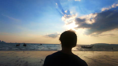 Man-filmed-from-behind-walking-towards-the-beach-in-slow-motion-at-sunset