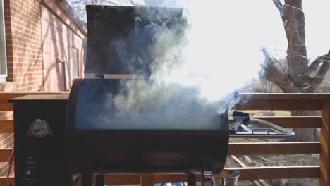 Smoke-coming-from-a-grill-while-warming-up-and-getting-ready-to-cook-on-a-wood-pellet-grill-during-the-evening