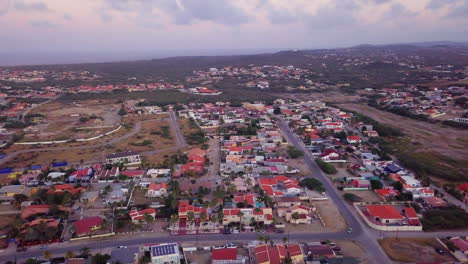 Calles-Residenciales-De-Aruba-Con-Autos-Conduciendo-Y-El-Mar-Caribe-En-El-Fondo