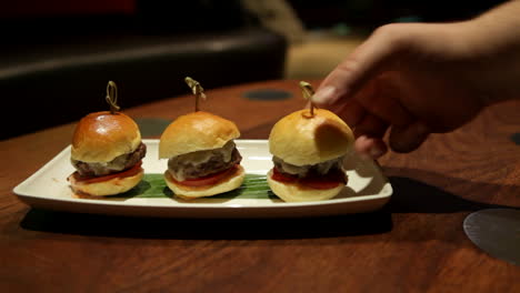 A-tray-of-delicious-Beef-Sliders-is-served-at-a-restaurant-as-a-male-customer-grabs-a-slider-to-eat
