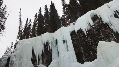 Wide-shot-of-woman-ice-climbing-on-frozen-water-fall
