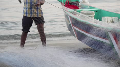Slow-motion-unidentified-Indian-fisherman-preparing-net-to-boat-in-Fort-Kochi,-India