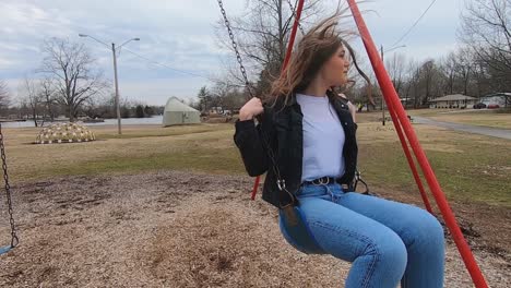 60-fps-footage-of-a-beautiful-brunette-college-teenager-swinging-on-a-swing-set-in-a-city-park