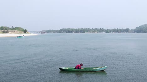 A-fisherman-sitting-in-a-kayak-boat-at-mandovi-river,-Goa