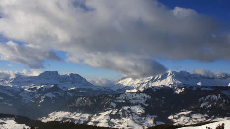 Zeitraffer-Einer-Winterlichen-Bergszene-In-Den-Französischen-Alpen,-Die-Wolken-Zeigt,-Die-über-Berggipfeln-Ziehen,-Mit-Blauem-Himmel-Und-Blick-Auf-Das-Tal