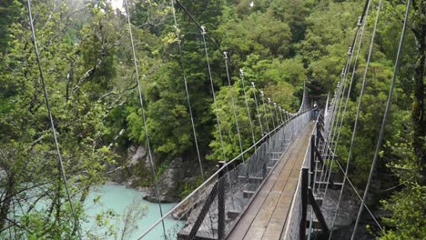 SLOWMO---Person-stands-on-suspension-bridge-over-glacier-river-at-Hokitika-Gorge,-New-Zealand