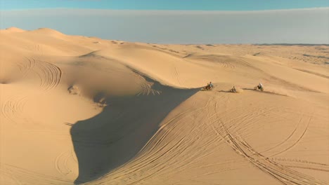 Luftaufnahmen-Von-Wüstensanddünen-Mit-Motocross-Fahrern-Und-Einem-Laufenden-Mann