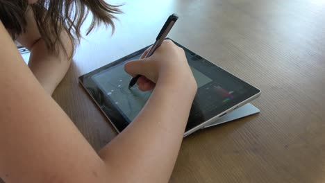 Girl-drawing-on-a-graphics-tablet,-over-the-shoulder-shot