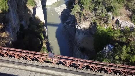Überflug-Eines-Menschen,-Der-Auf-Einer-Alten-Rostigen-Holzbrücke-über-Der-Osumi-Schlucht-In-Der-Nähe-Von-Corovode-In-Albanien-Sitzt