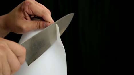 sharp-knife-cutting-paper-with-ease,-demonstration-of-a-sharp-chef-knife