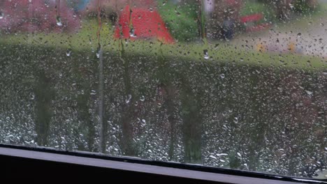 Regen-Fällt-Auf-Die-Fensterbank-Und-Tropft-Auf-Die-Oberfläche,-Mit-Der-Stadt-Im-Hintergrund,-Standbild-In-Mittlerer-Nahaufnahme