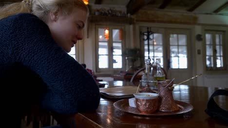 Blonde-woman-in-a-blue-sweater-smiling-at-a-Turkish-coffee-service