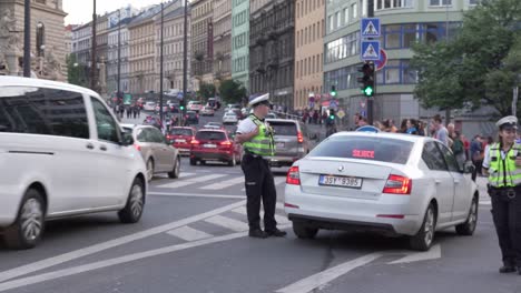 Polizisten-Kontrollieren-Den-Verkehr-Und-Blockieren-Die-Einfahrt-Mit-Einem-Polizeiauto,-Das-Blaue-Lichter-Blinkt