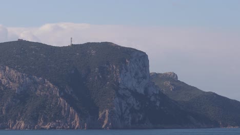 Massive-cliffs-island-as-seen-from-the-open-water-blue-sea-with-pale-cloudy-sky