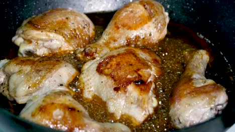 Delicious-chicken-pieces-cook-in-pan-of-bubbling-sauce,-slow-motion-closeup