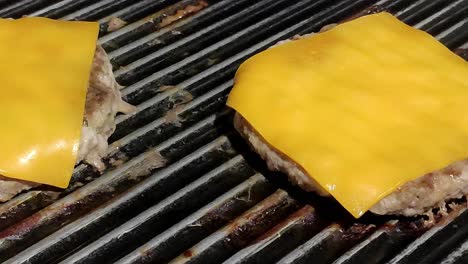 two-homemade-cheeseburgers-cooking-on-a-black-grill