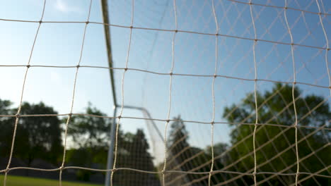 Close-up,-looking-through-a-soccer-net-in-the-early-morning-sun