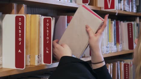Frau-Bringt-Bücher-Zurück-Zu-Den-Bücherregalen-In-Der-Bibliothek,-Detail-Ihrer-Hände