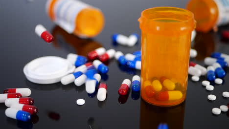 Many-prescription-pills,-drugs-and-capsules-falling-in-slow-motion-on-an-orange-pharmacy-medicine-bottle