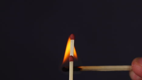 Ignition-of-two-matchsticks-close-up-macro-shot-captured-from-left-side-and-fire-from-bottom-on-black-background-in-slow-motion-at-120-fps