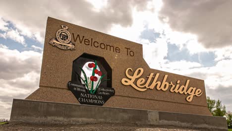 A-slow-moving-timelapse-of-clouds-going-over-the-city-of-Lethbridge,-Alberta-welcome-sign
