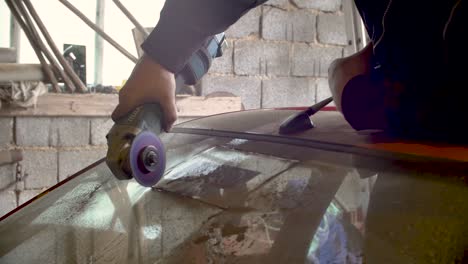 Male-cutting-windshield-glass-with-fast-spinning-cutting-saw-slow-motion-garage-scene,-to-get-out-vignette