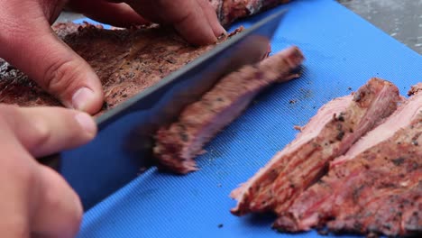 Slicing-several-pieces-of-tender-meat-on-a-blue-rubber-mat-for-a-BBQ-cook-off-competition