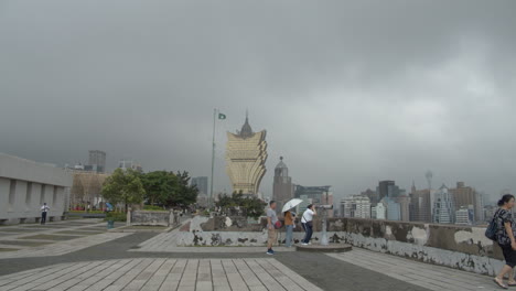 Time-lapse-of-tourists-passing-back-and-forth-watching-Macau-cityscape-from-top-of-Mount-Fortress-,-with-hotel-Grand-Lisboa-in-the-background,-in-Macau-SAR,-China