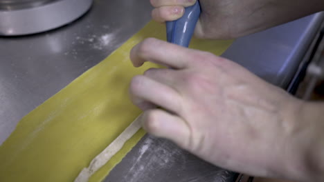 Pasta-filling-being-piped-onto-a-sheet-of-rolled-dough