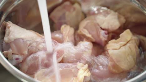 Extreme-close-up-of-a-bowl-of-raw-chicken-being-rinsed