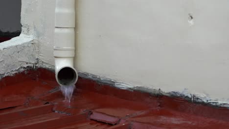Rainwater-from-the-top-gutter-pours-out-of-a-residential-drainage-spout-during-a-drizzle