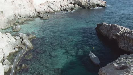 Slow-aerial-flight-along-the-slipway-of-an-old-fishing-Village-at-Ghar-Lapsi-in-the-Siggiewi-province-of-Malta,-A-popular-tourist-destination-due-to-crystal-blue-waters