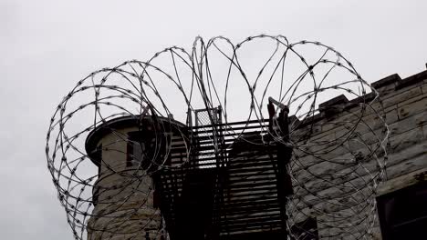 close-up-barbed-wire-prison-guardhouse-timelapse-under-gray-cloudy-sky-4k
