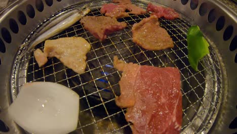 Tongs-grilling-raw-meat-on-yakiniku-Japanese-BBQ
