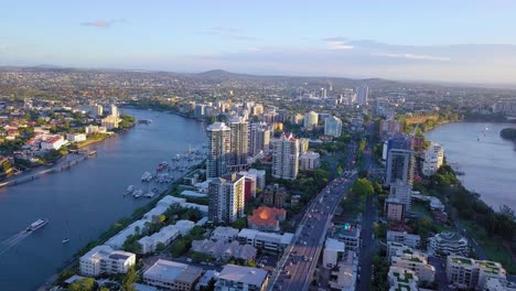 Panning-aerial-view-of-a-Brisbane-city-with-busy-street-and-river-curve-in-the-evening