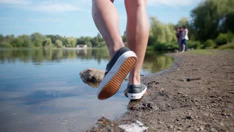 Walking-across-the-shore-of-a-lake-and-jumping-onto-a-rock