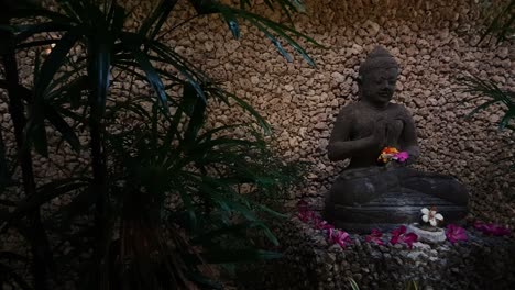 Eine-Schwenkansicht-Einer-Wunderschön-Dekorierten-Balinesischen-Statue,-Die-Zwischen-Einer-Wand-Und-Grünem-Blattwerk-Positioniert-Ist