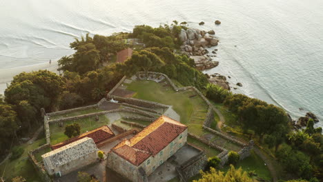 Top-down-view-of-famous-landmark-brazilian-fortress-at-sunset,-Fortaleza-Sao-Jose-Da-Ponta-Grossa,-Jurere-Internacional,-Florianopolis,-Santa-Catarina,-Brazil