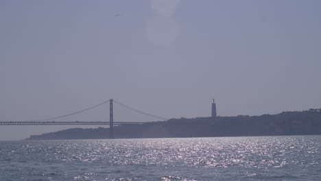 Lisbon-bridge-statue,-shot-by-boat