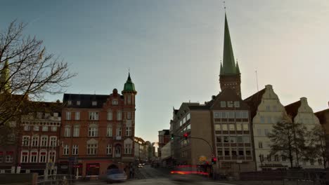 Pan-down-time-lapse-of-a-busy-intersection-in-Lübeck,-Germany,-with-St