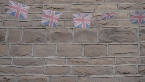 Wimpel-Mit-Britischer-Union-Jack-Flagge,-Die-Im-Wind-An-Einer-Wand-Hängt