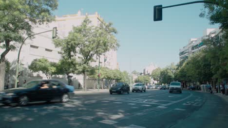 Autos-Und-Motorräder-Fahren-Auf-Einer-Belebten,-Schattigen-Straße-In-Sevilla,-Spanien