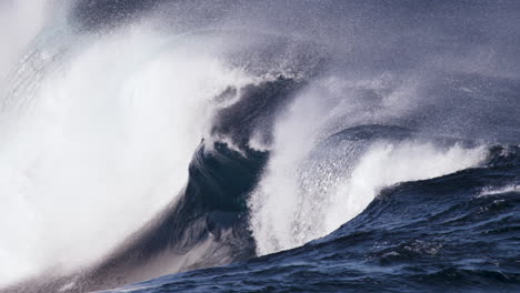 A-glassy-wave-surges-along-a-shallow-rock-shelf-in-slow-motion-while-the-offshore-winds-blow-spray-back-up-the-wave-face