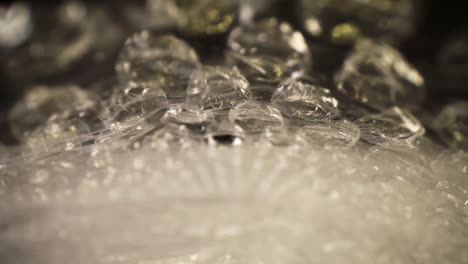pushing-into-a-bubble-wrap-bag,-where-the-bag-is-really-close-to-the-lens-as-it-cascades---rolls-away-as-it-moves-through