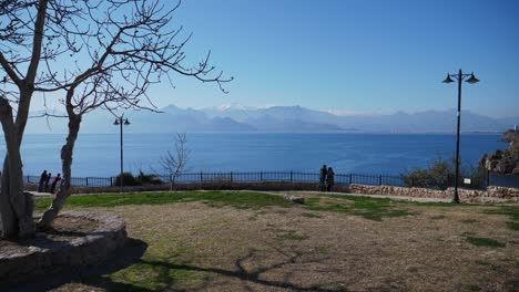 Full-shot,-couple-standing-besides-the-railing,-scenic-view-of-the-Mediterranean-sea-and-mountains-in-the-background