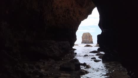 Viewing-a-limestone-rock-stack-through-the-opening-of-a-sea-cave-near-Lagos,-Portugal