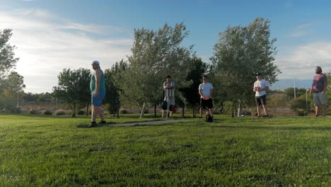 Guys-taking-turns-to-throw-their-discs-in-a-disc-golf-course