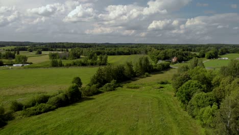 Aerial-footage-over-village-space,-beautiful-green-field,-fresh-grass-and-natural-landscape,-Eastern-Poland,-magical-sky-and-high-trees-on-horizontal
