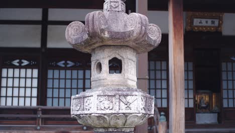 Old-Japanese-stone-lantern-sitting-in-front-of-an-old-temple-in-Kyoto,-Japan-close-up-shot-4K