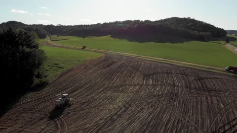 4K-aerial-landscape-view-of-a-harvester-driving-through-a-Finished-field-after-harvest
